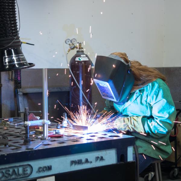 student working on metal artwork using welder