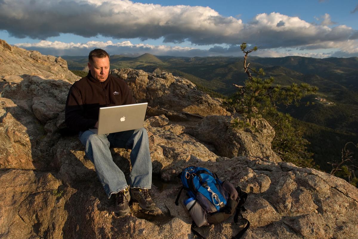 student with computer in scenic Boulder Colorado mountains