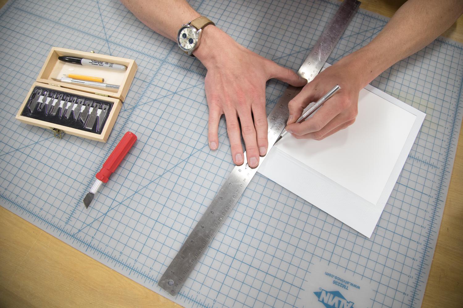 Students hands working on cutting a photograph in our digital output lab