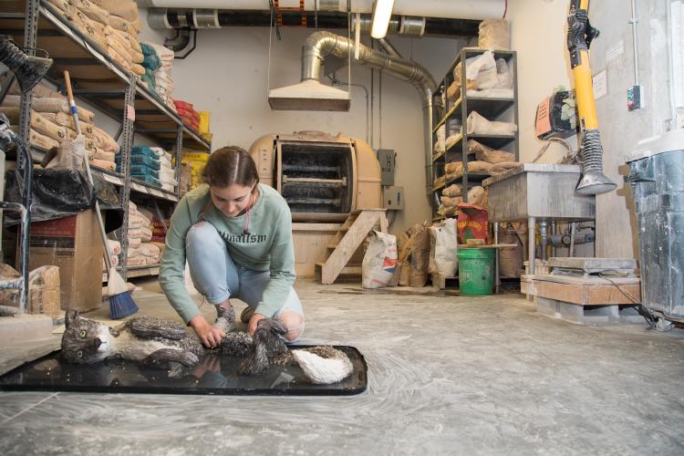 Student working on clay piece in the kiln room