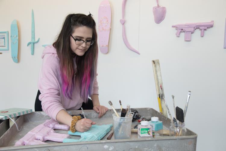 BFA Candidate, Lexie Lund, making finishing touches to her BFA project and installing on the first floor lobby for the BFA exhibit in the VAC.