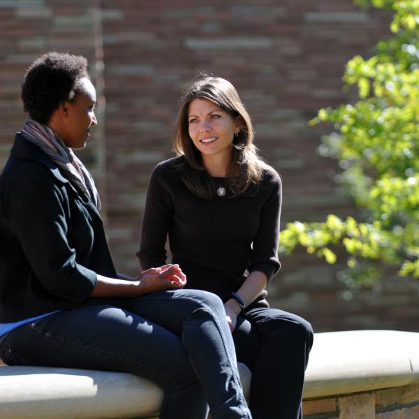 Two faculty members sitting and talking outside