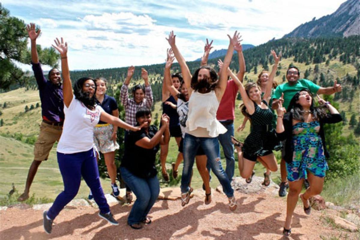 A large group of students jump together at the Mount Sanitas trail in Boulder, Colorado.
