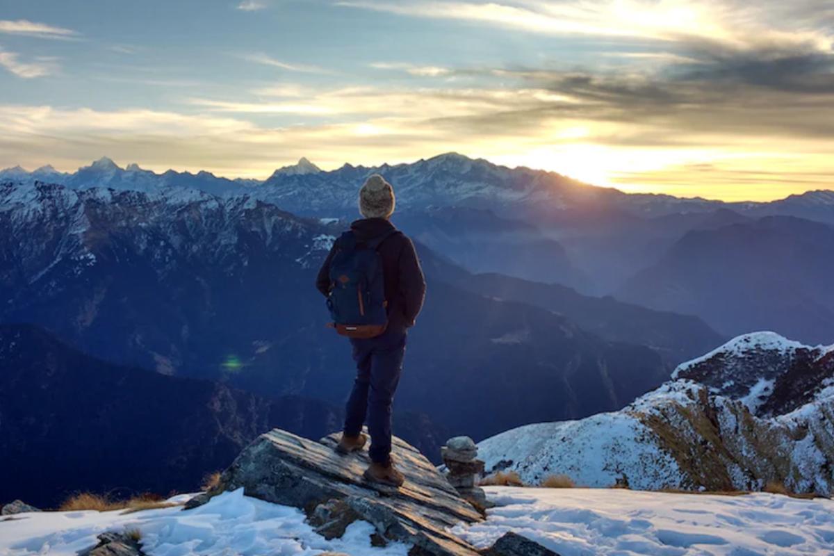 Person enjoying a view of the mountains covered in snow