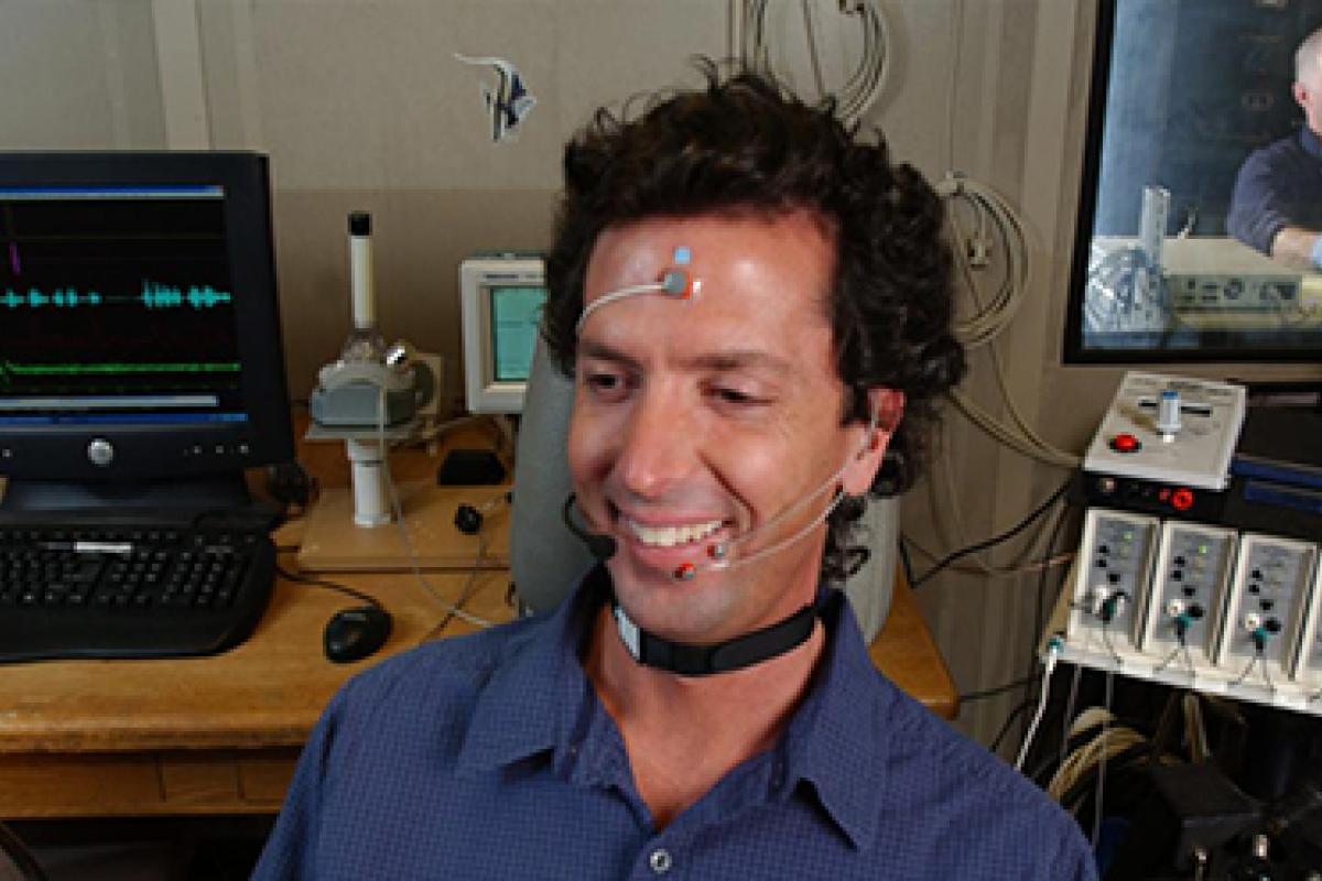 A person smiles as he conducts a research study on a technology meant to improve hearing.