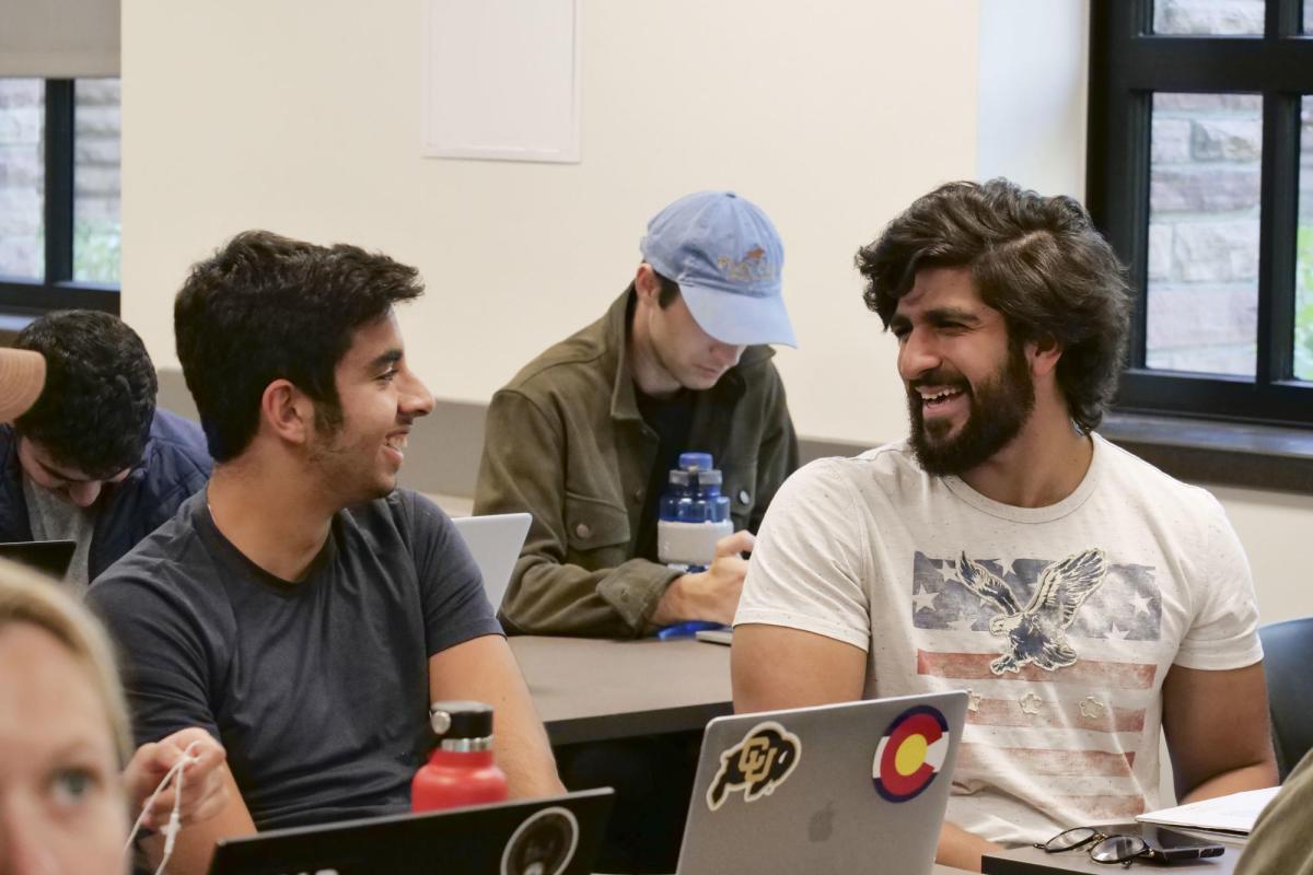 Two students discuss a concept, laughing in class.