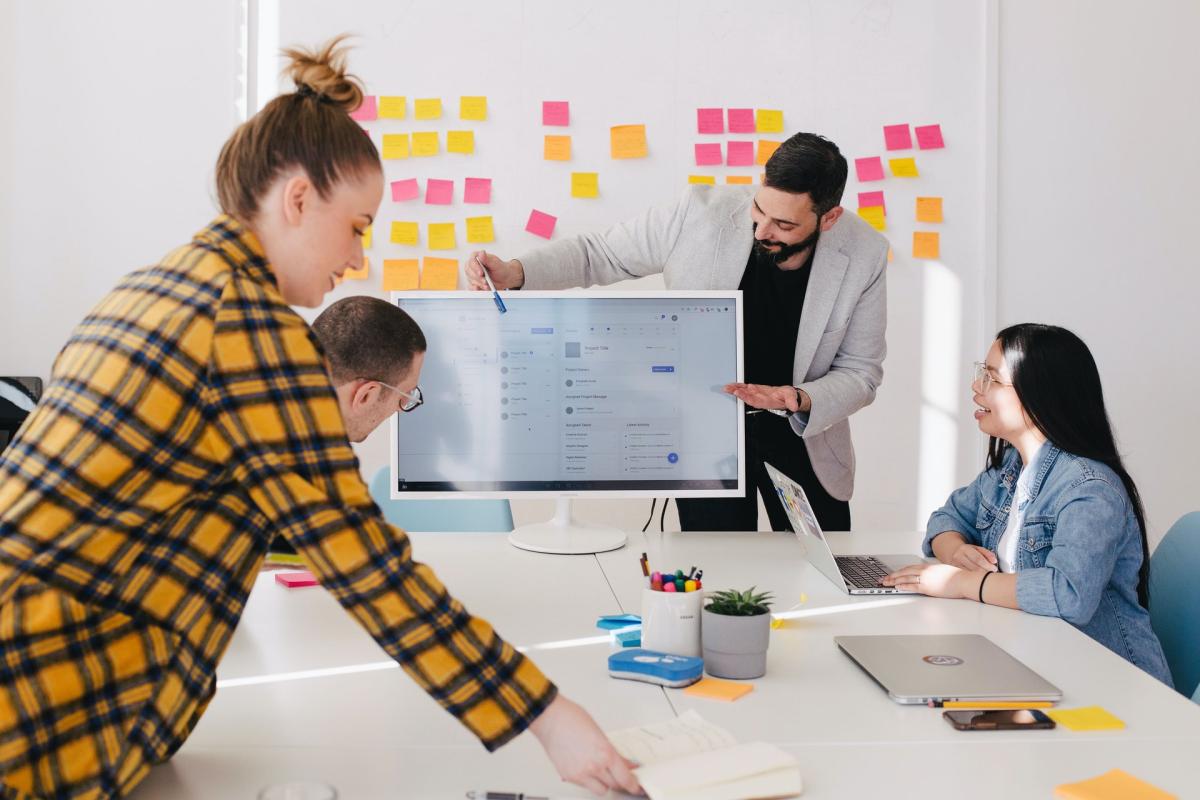 Several people huddle around sticky notes while brainstorming a new idea.