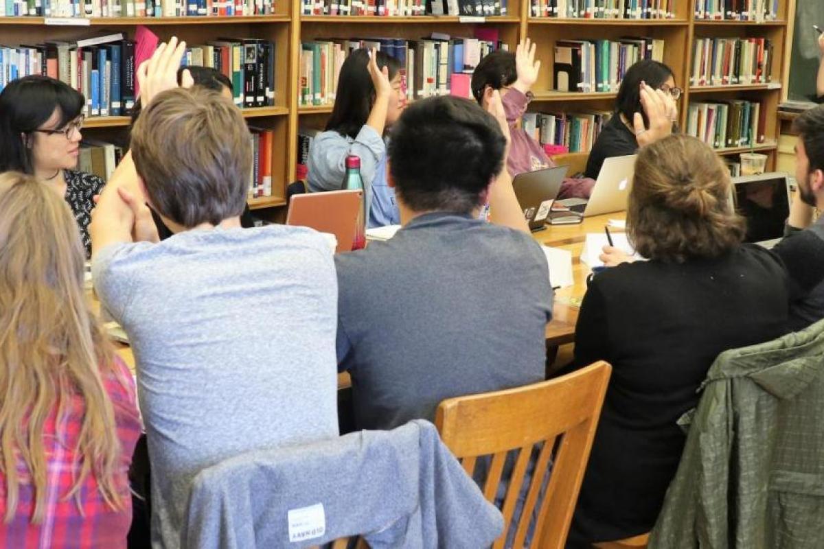 Student raise their hands in a small seminar