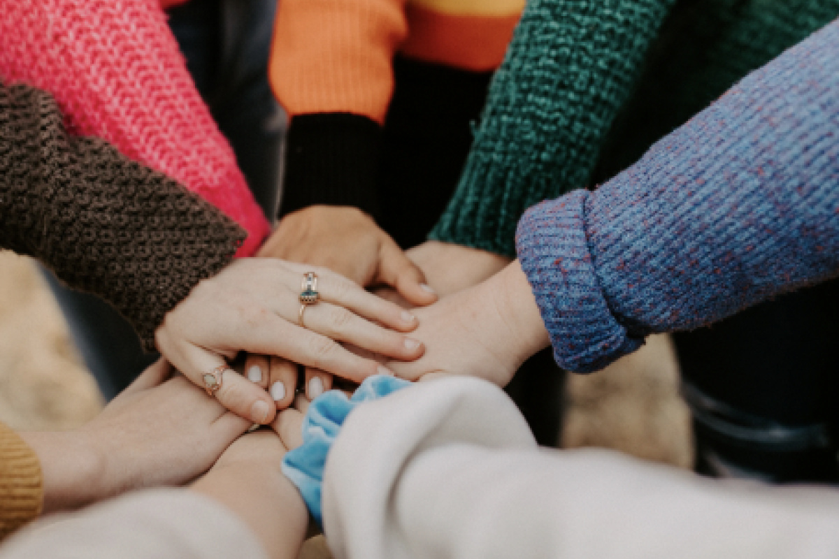 A group of people placing their hands in the middle of a circle showing unity and togetherness