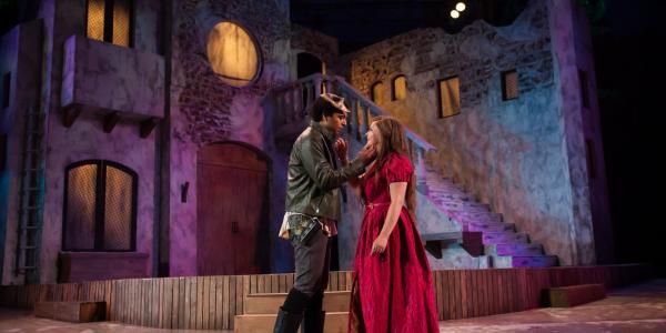 Romeo and Juliet hold each other in an embrace on stage