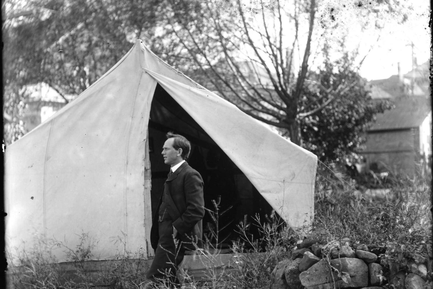 Fred Hellems stands in front of a tent in an old photograph.