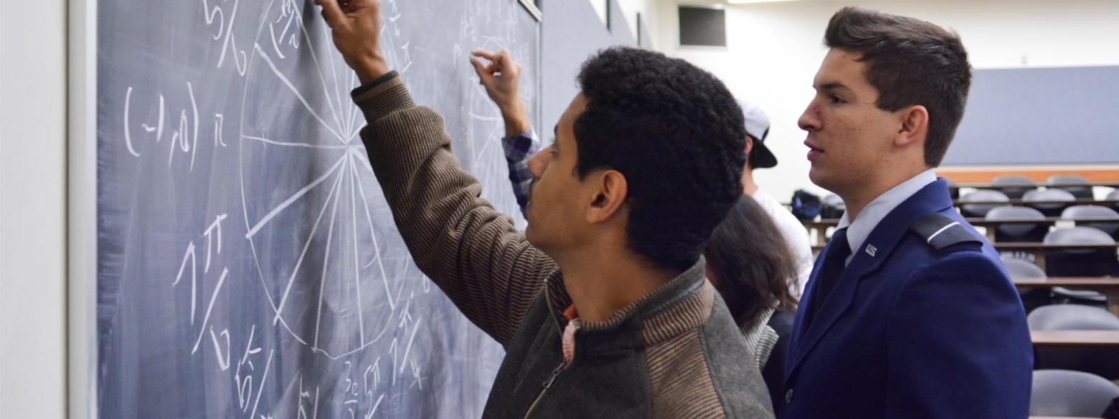 Students solve a math problem on a chalkboard