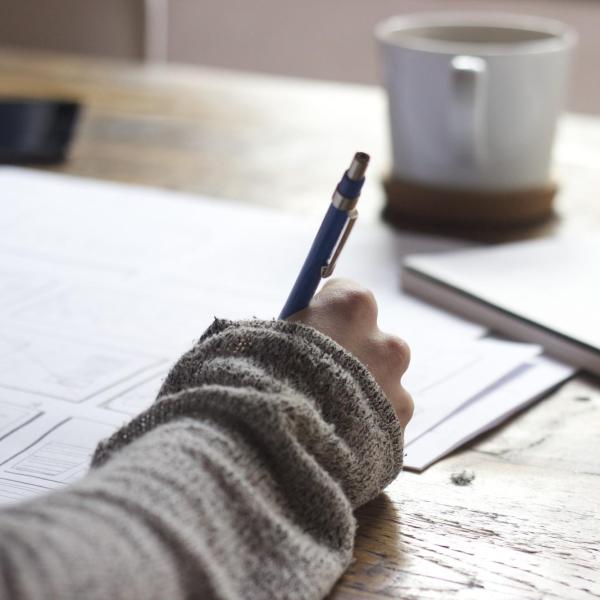 person writing at a messy desk