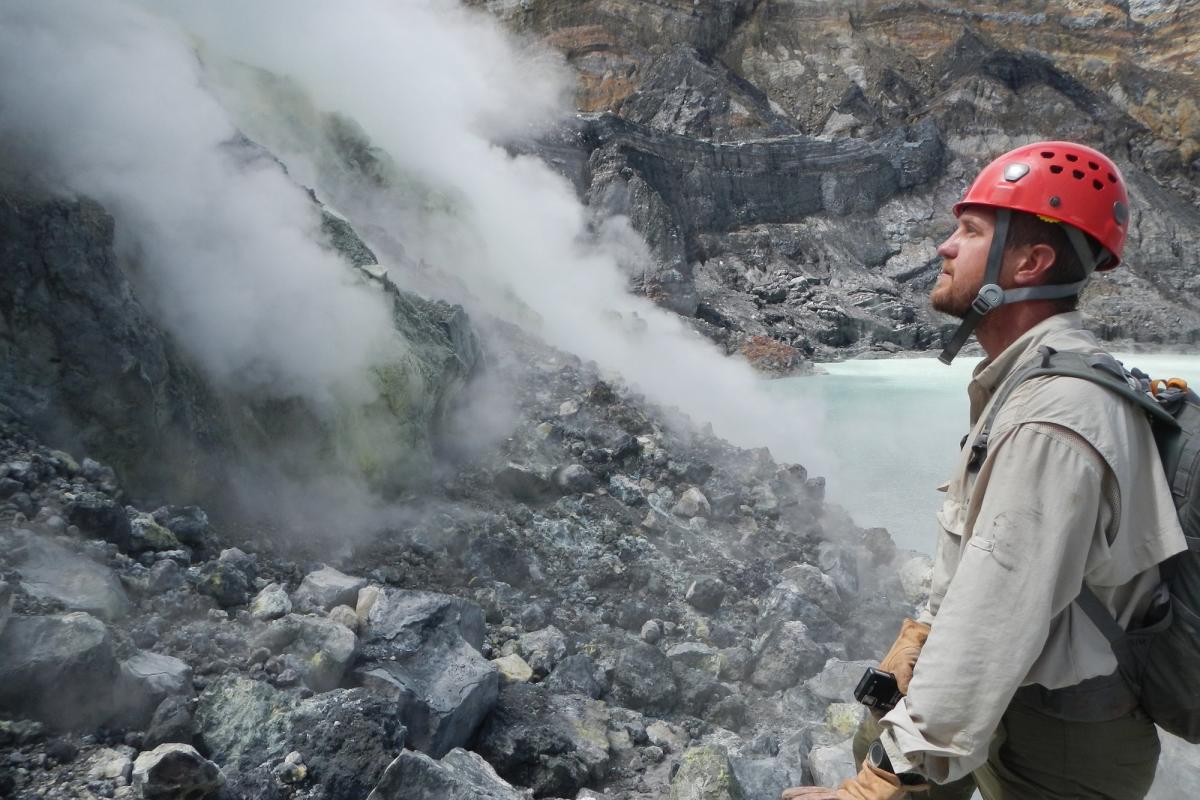 grad student looking at steam vents on rock field