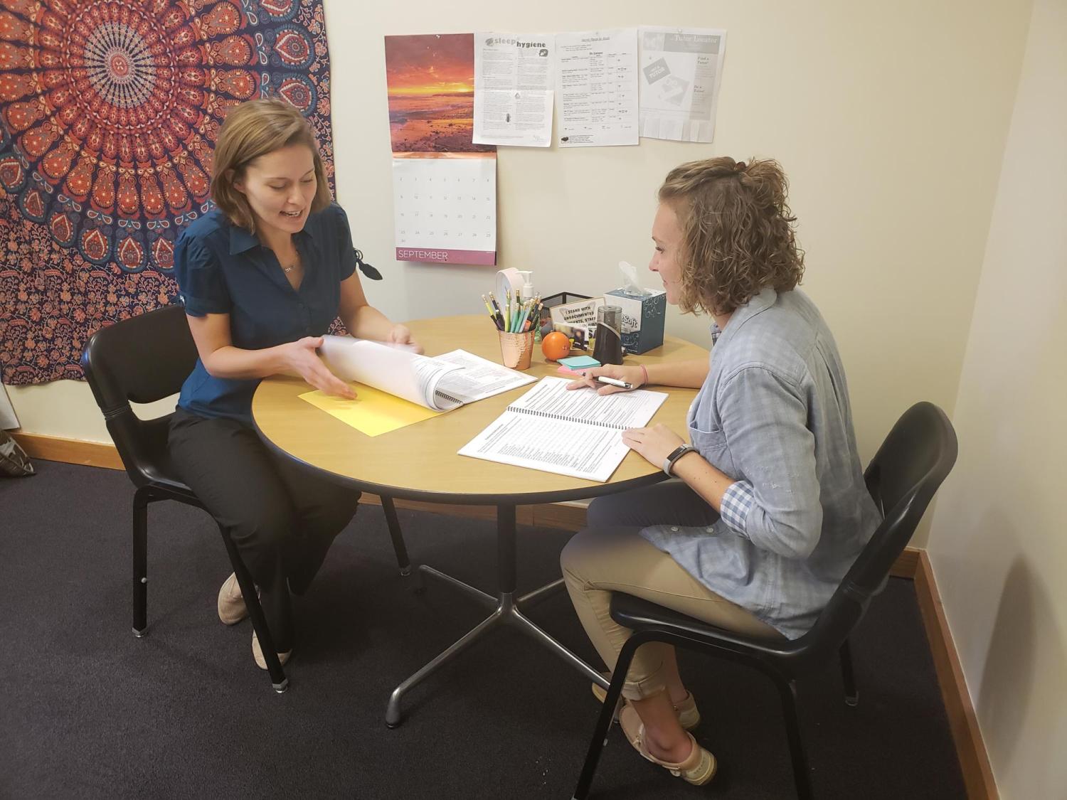 An academic coach and student sit as a table to discuss study strategies.