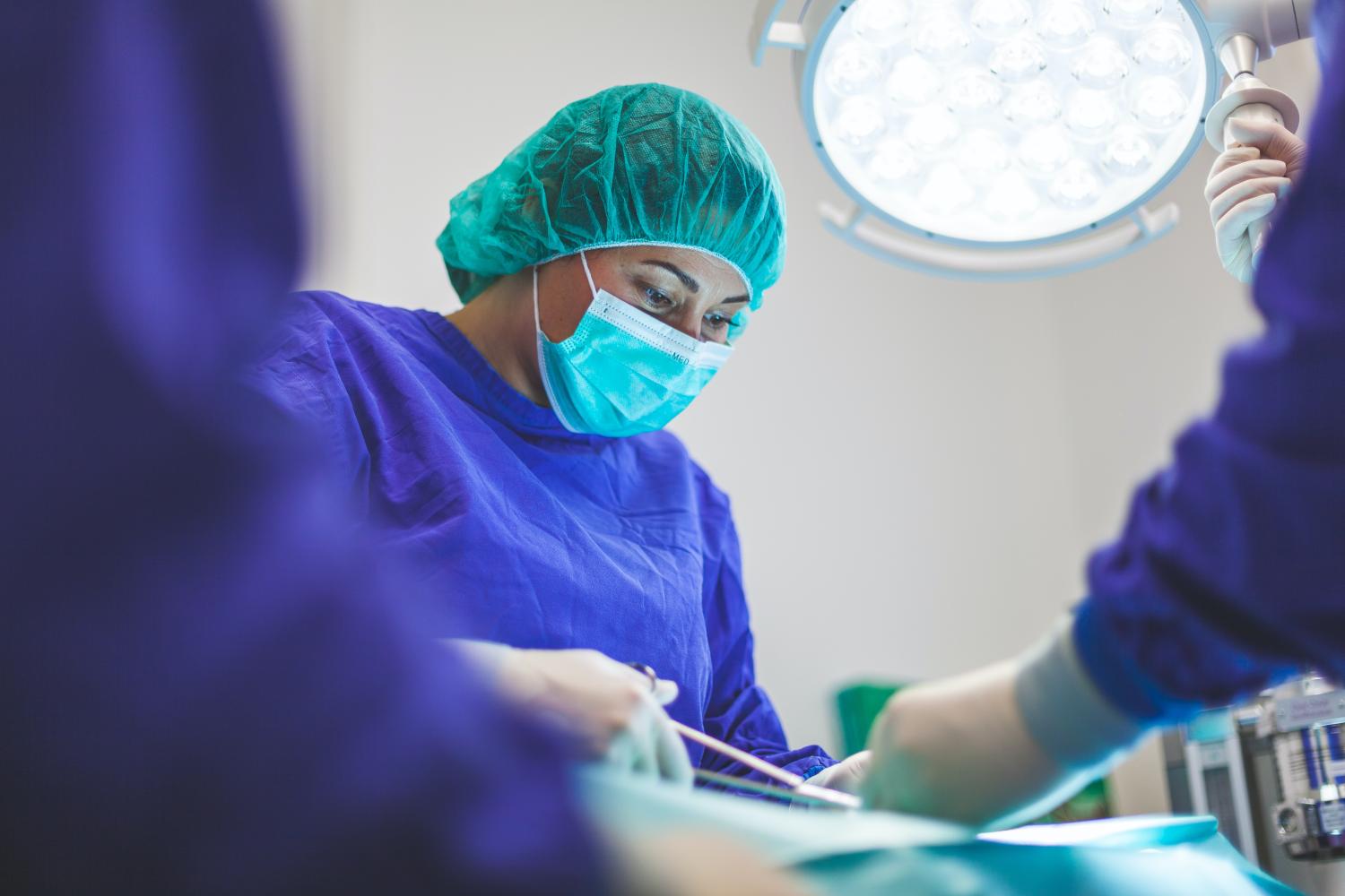 A surgeon conducts surgeon under the bright lights of an operating room