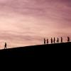 The shadowed outline of a single individual appears somewhat separate from a small group trailing behind.