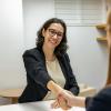 A well-dressed person smiles and appears to reach out to shake someone's hand.