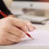 A hand fills out a scantron exam sheet.