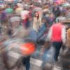 One woman appears clear in a blurred crowd of passersby.