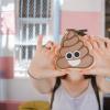 A woman holds a poop emoji cookie in front of the camera.