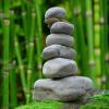A cairn of gray river stones is stacked against a bamboo forest.