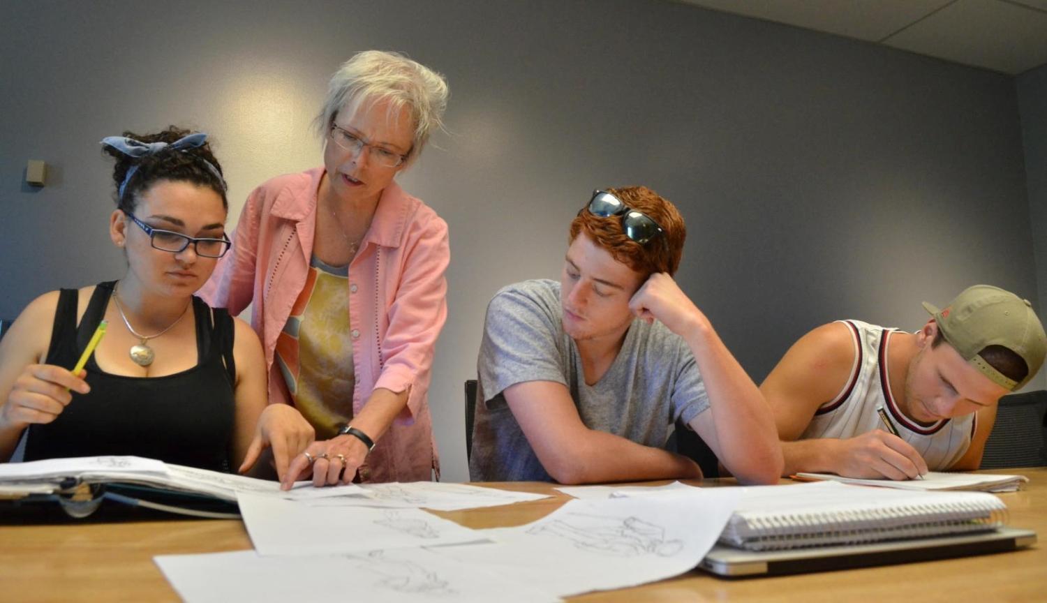 Professor helping students at table