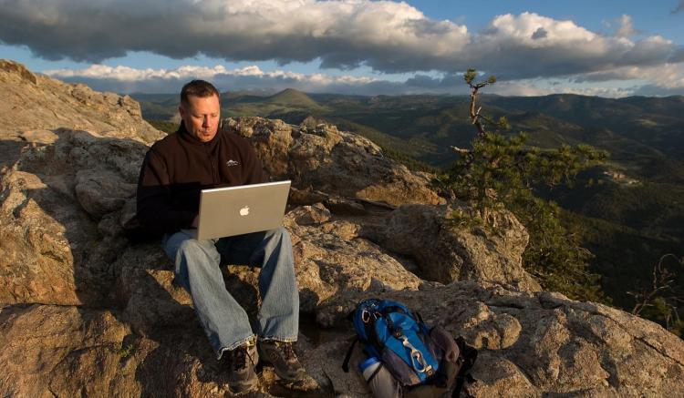 Man with laptop in mountains