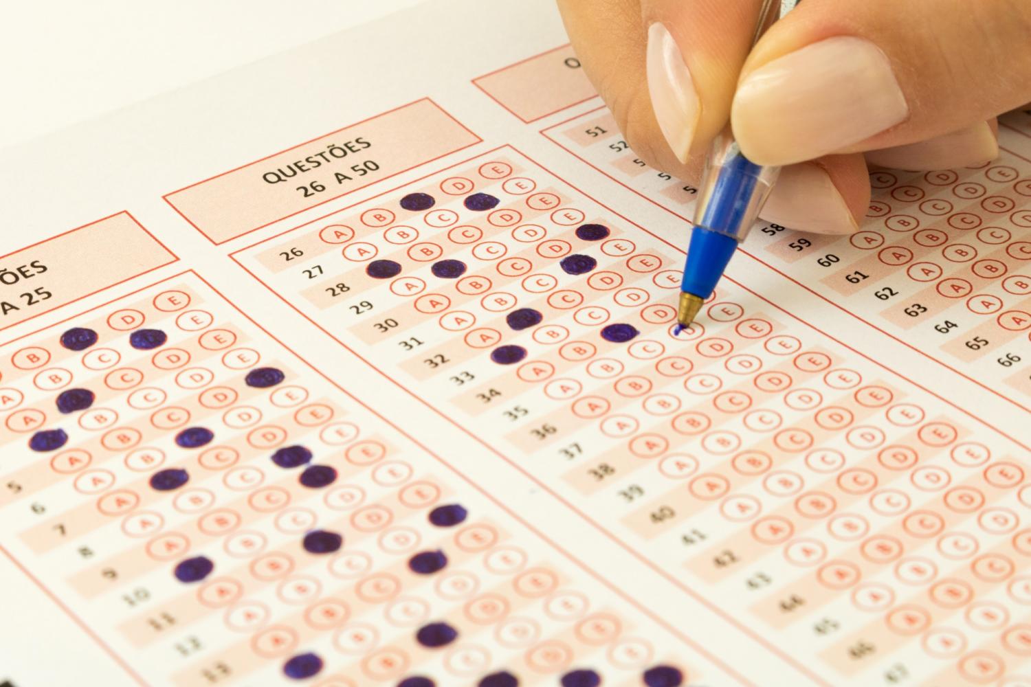 hand holding blue pen, filling in multiple choice sheet