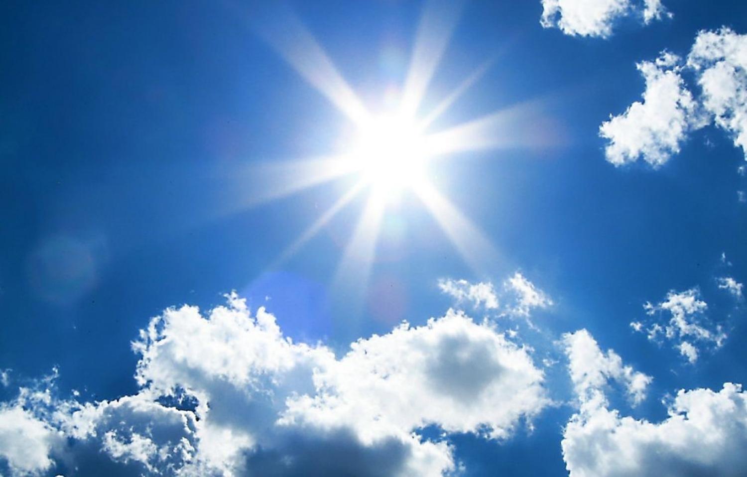 sun shining in blue sky with several clouds