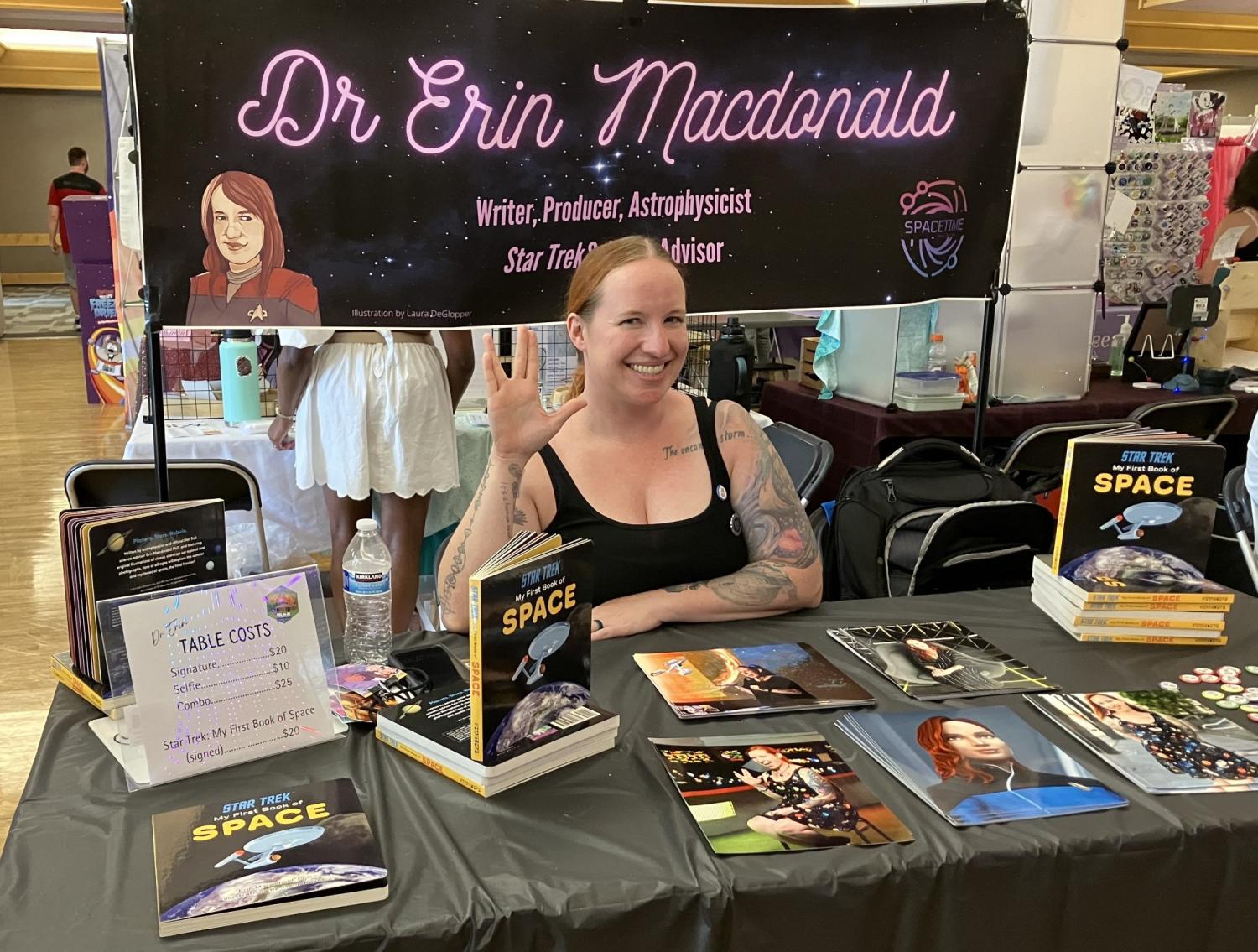 Erin Macdonald at merchandise table flashing Vulcan "live long and proper" hand symbol