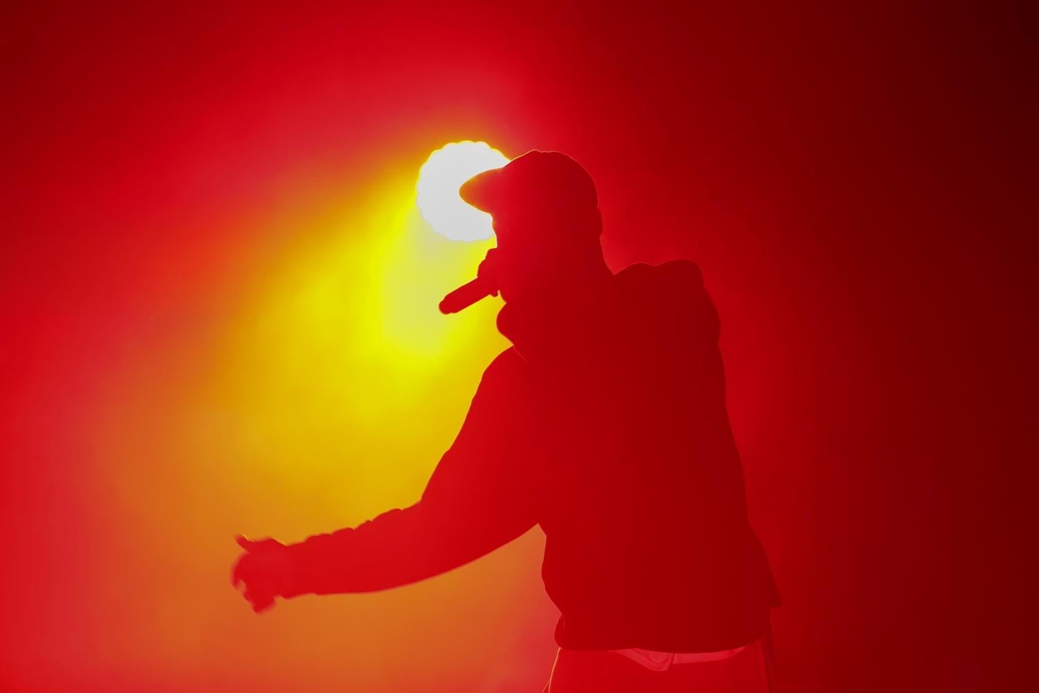 hip hop performer onstage silhouetted against yellow stage light
