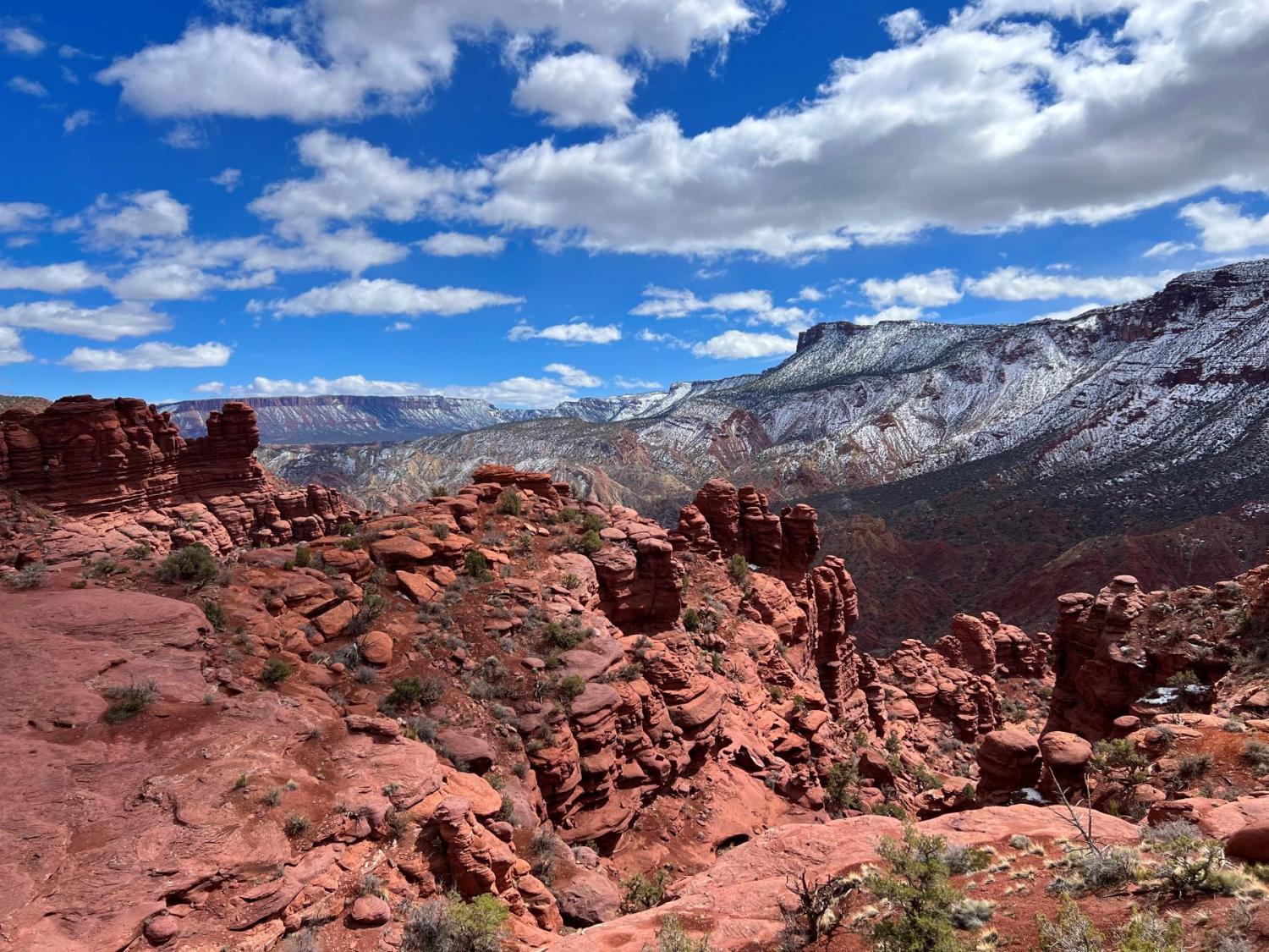 Red rock and Colorado mountains under blue sky with scattered clouds