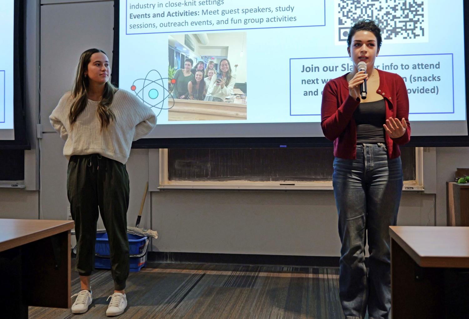 Annalise Cabra holds microphone and Emily Jerris looks on as they present about CU Women of Quantum