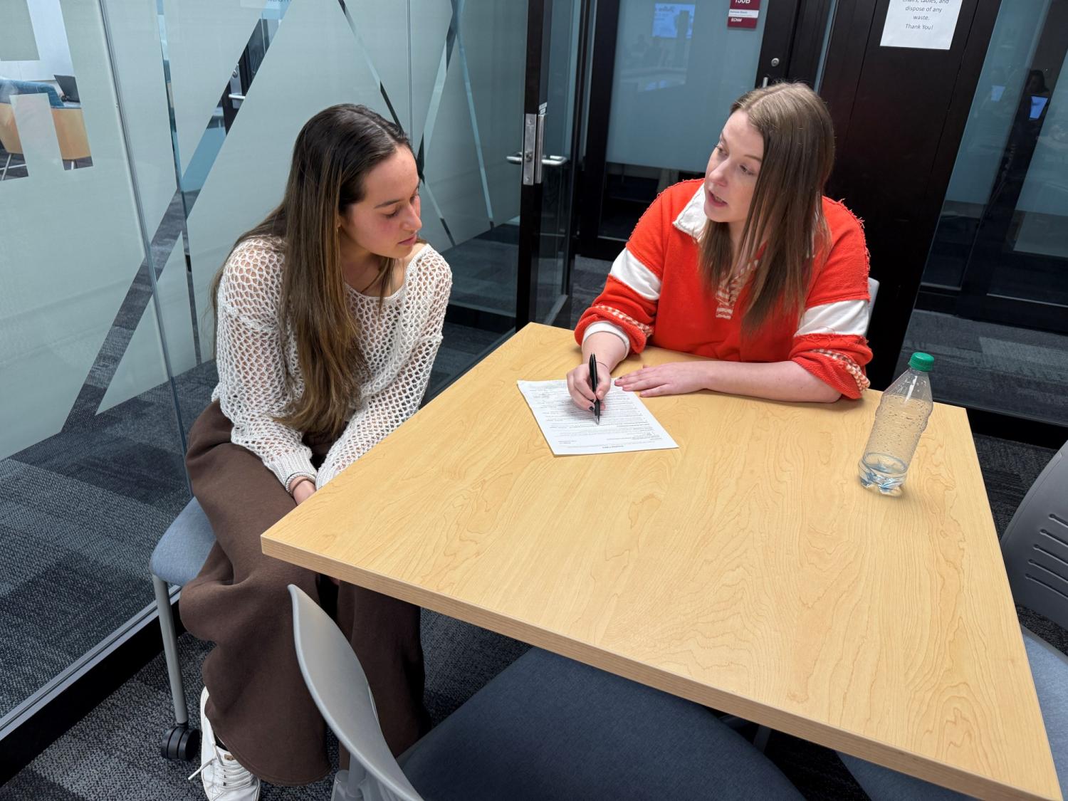 Annalise Cabra and Brooke Nelson sitting at table looking at Annalise's paper resume