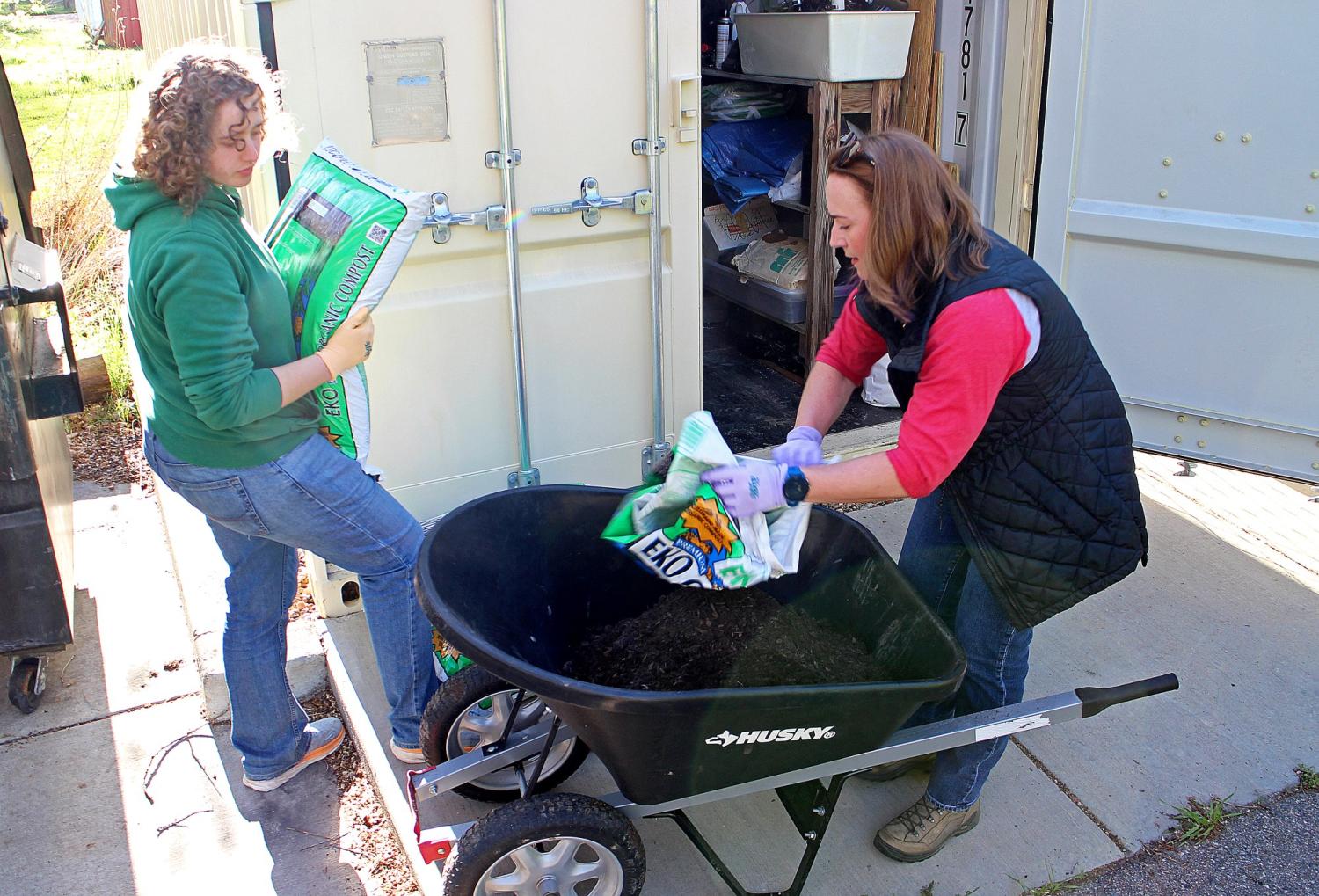 Sophie Small and Amy Dunbar-Wallis putting compost in a wheelbarrow