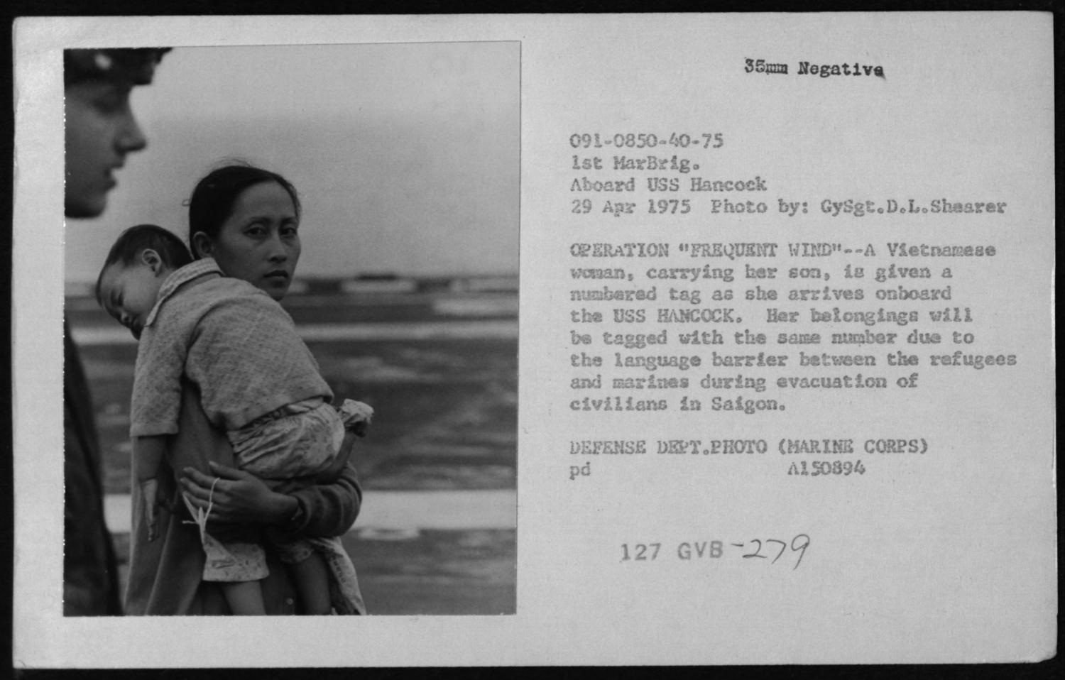 woman carrying sleeping son on deck of U.S.S. Hancock on April 29, 1975