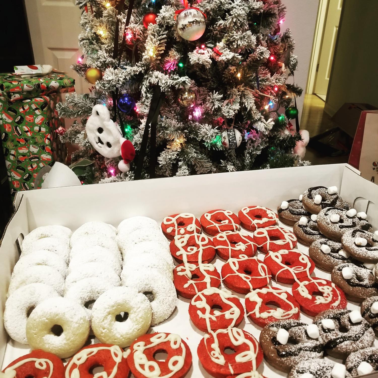 boxes filled with donuts in front of decorated Christmas tree