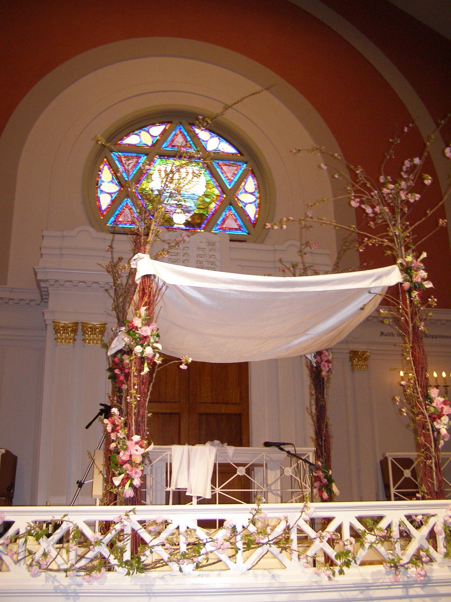 a chuppah inside a synagogue beneath a Star of David stained glass rose window