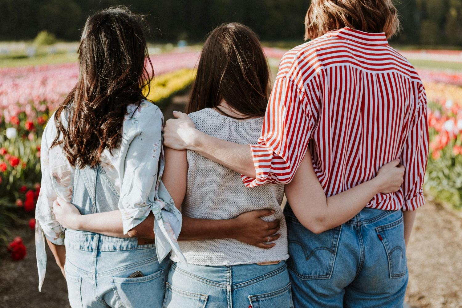 Three women shown from back with arms around each other
