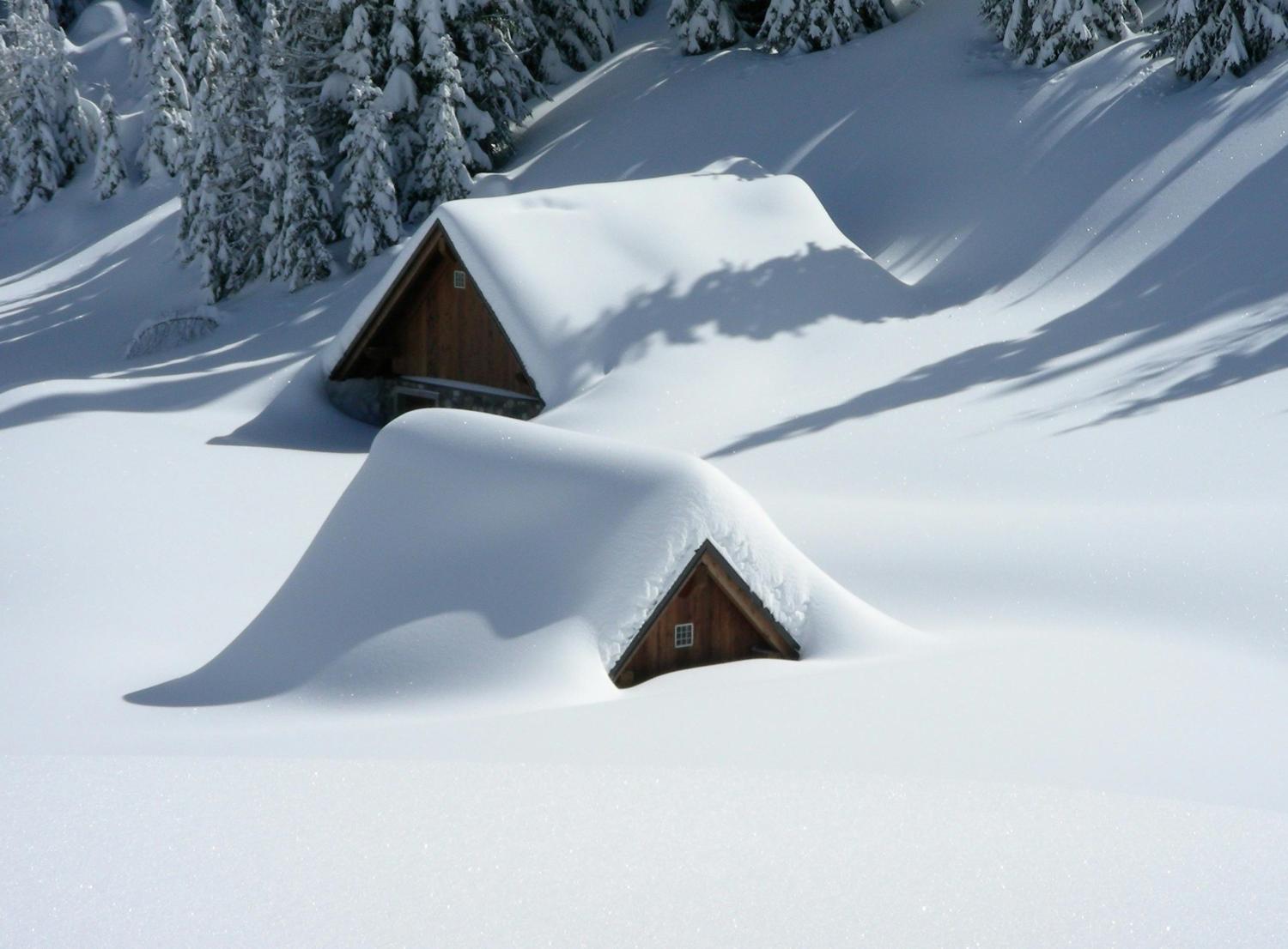 two cabin eaves barely visible in deep snow