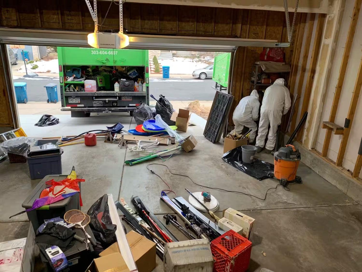 Two workers in white hazmat suits perform smoke remediation in a garage