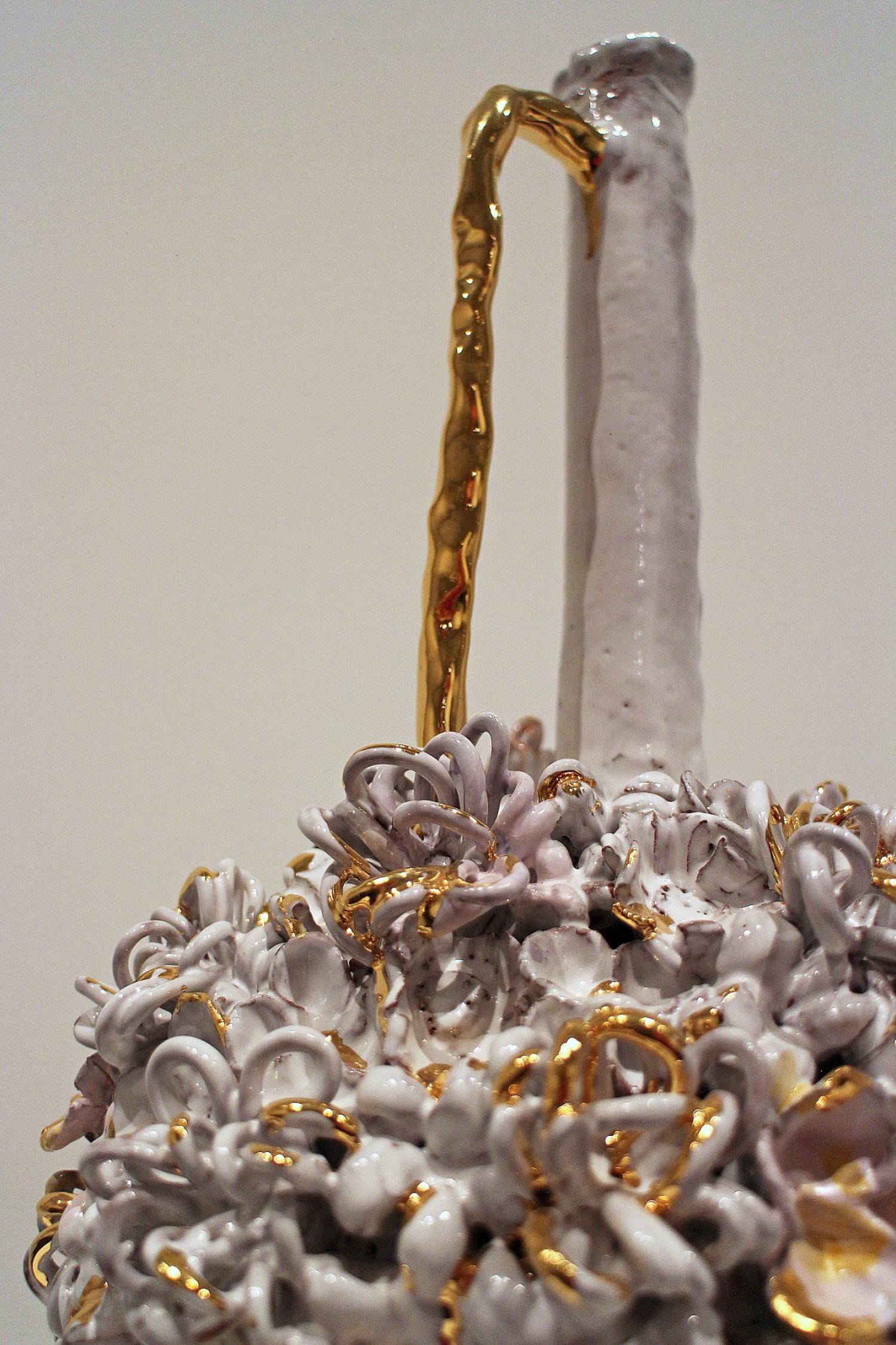 long-necked ceramic vessel with gold handle and textured floral design