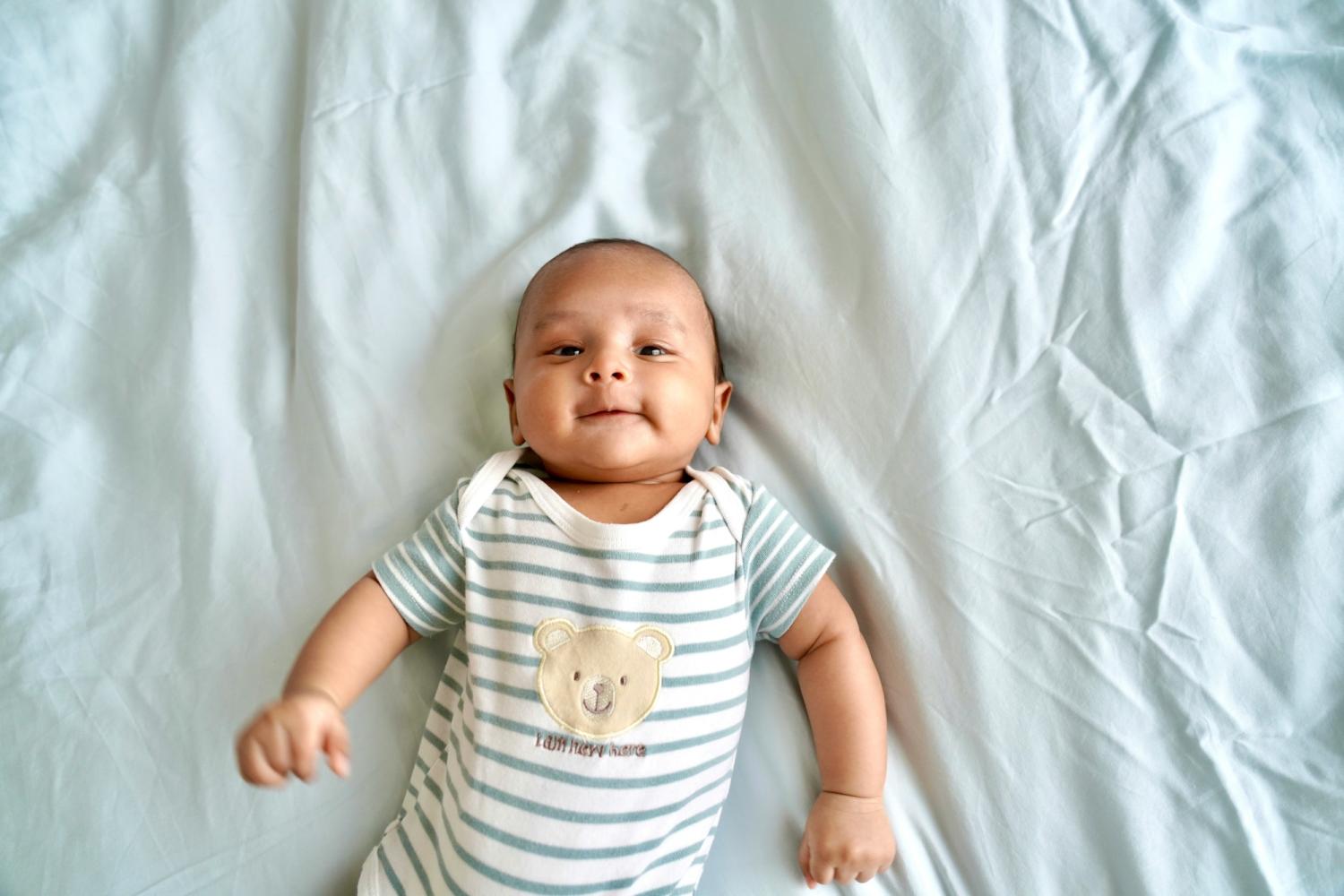 infant lying on back wearing striped onesie
