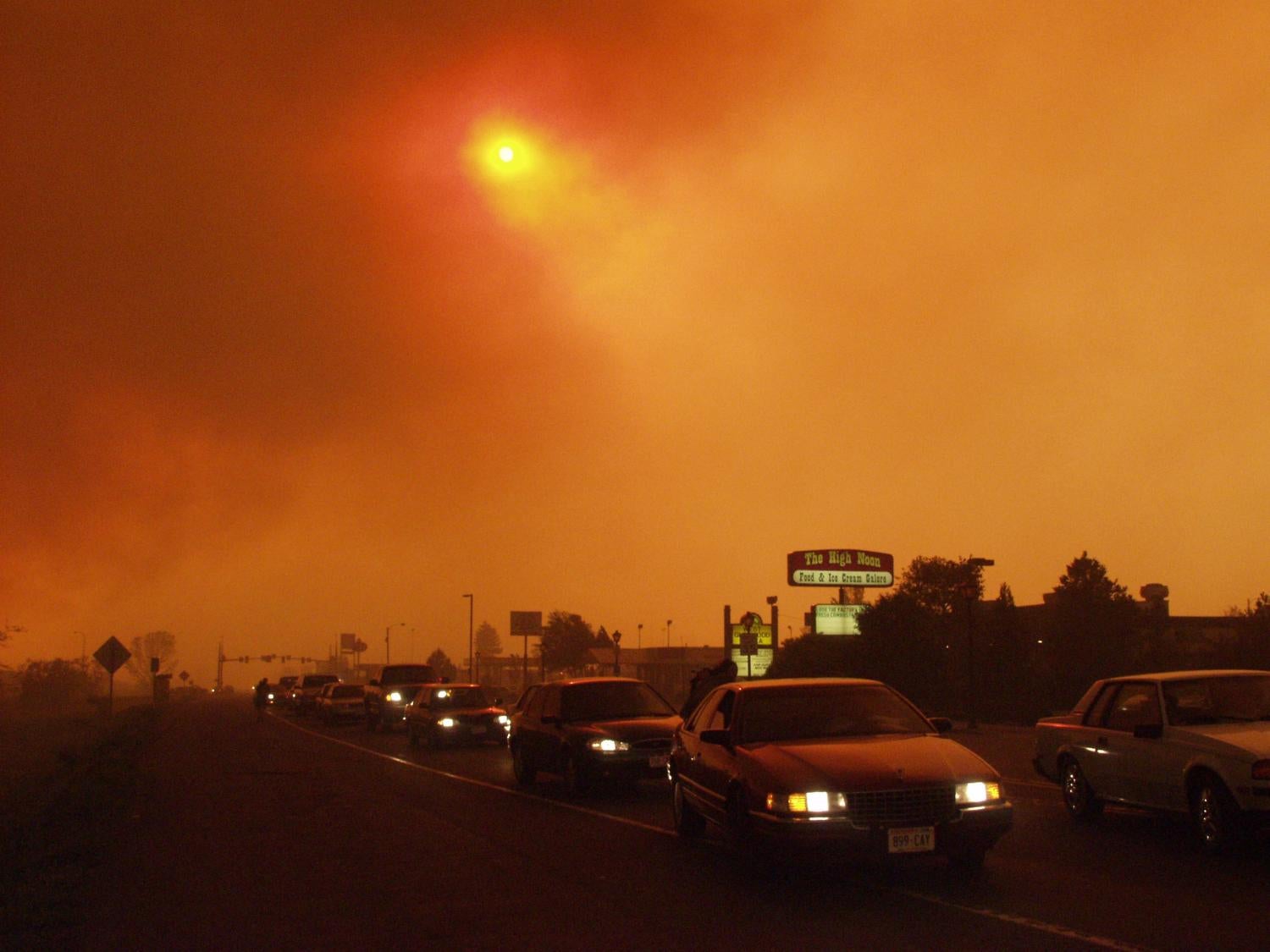 line of cars leaving Glenwood Springs under sky made orange by wildfires
