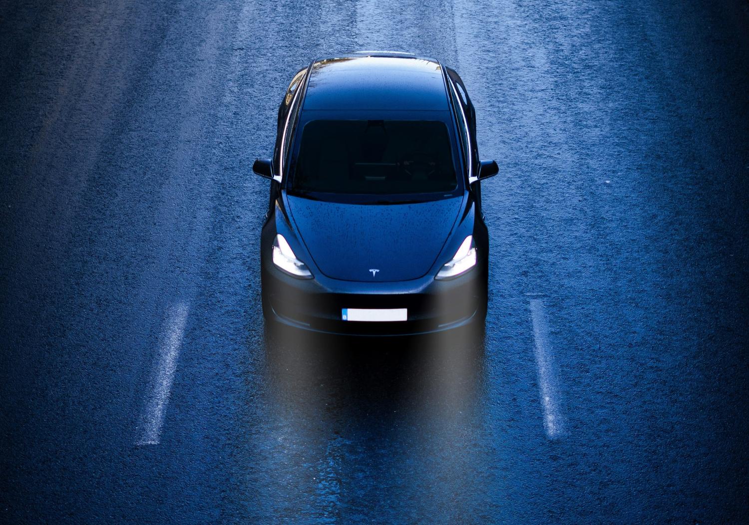 dark blue Tesla sedan driving on multi-lane road