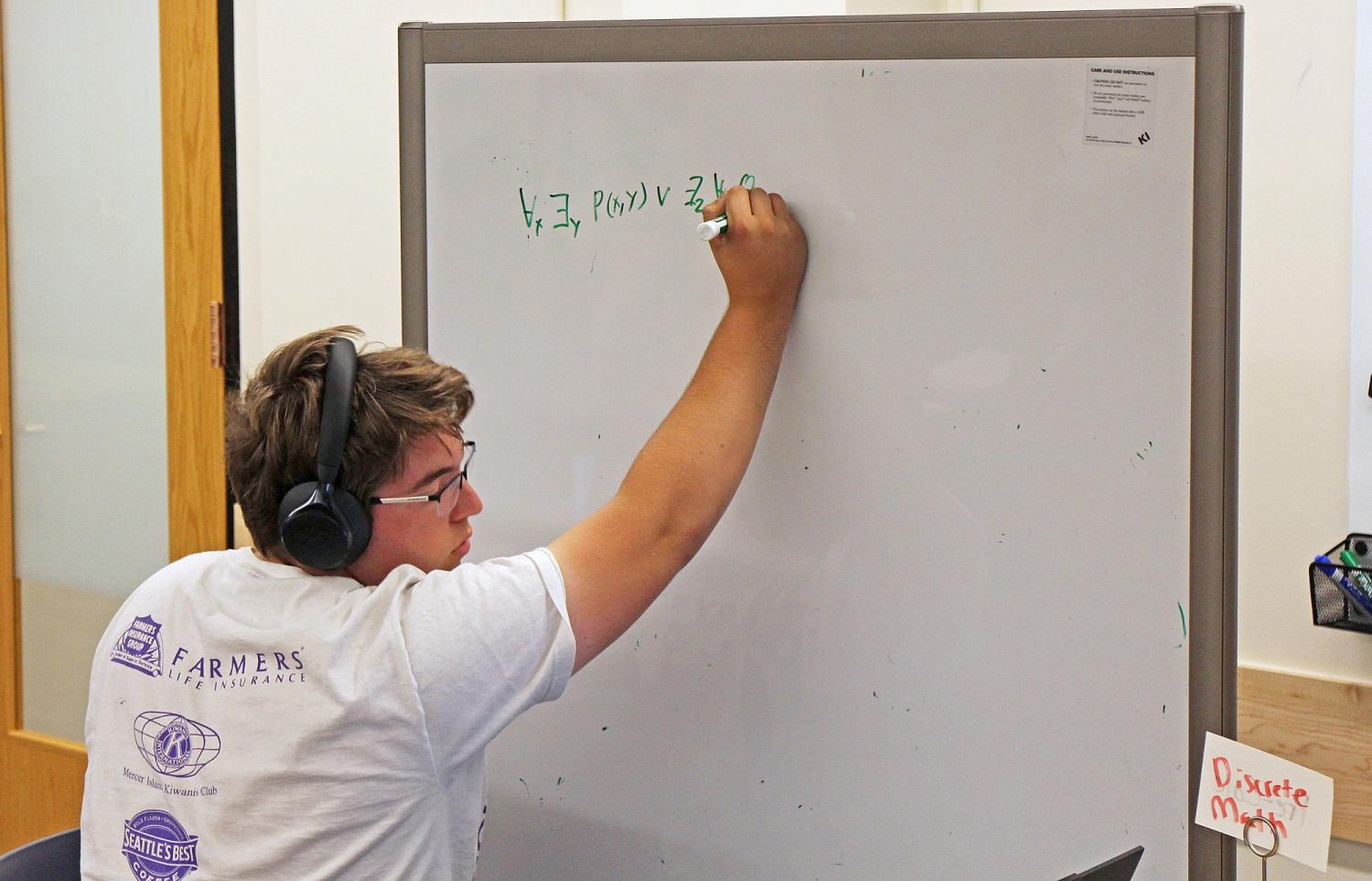 Ben Sewald wearing headphones and writing on whiteboard