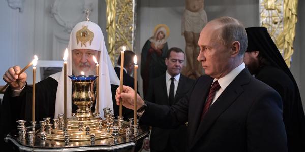 Russian President Vladimir Putin, accompanied by Patriarch of Russia Kirill and Prime Minister Dmitry Medvedev (in background), at a monastery outside Moscow in 2017.