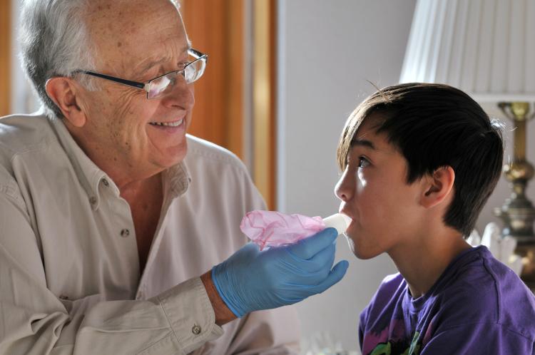 Bob Sievers, shown in 2011 with help from his then-11-year-old grandson Benjamin Louis Sievers, demonstrates how vaccines can be delivered by inhaling from a bag. Photo by Glenn Asakawa.