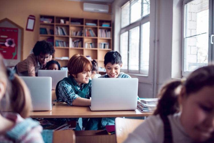 Two young students in front of a laptop